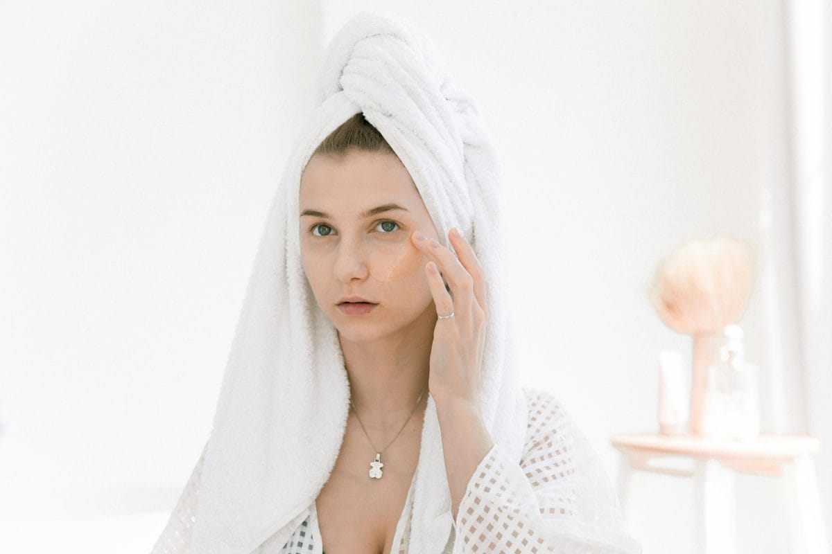 female with towel on her head touching face