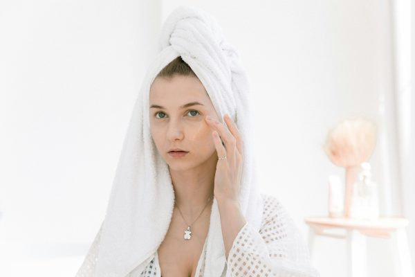 female with towel on her head touching face