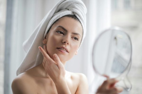 Female touching face looking in hand mirror