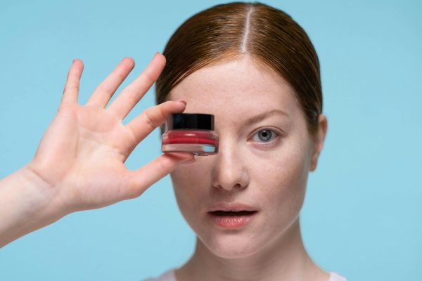 female holding skincare product in front of her eye