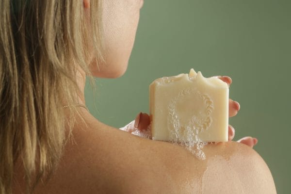 young caucasian woman holding soap bar on her shoulder. natural