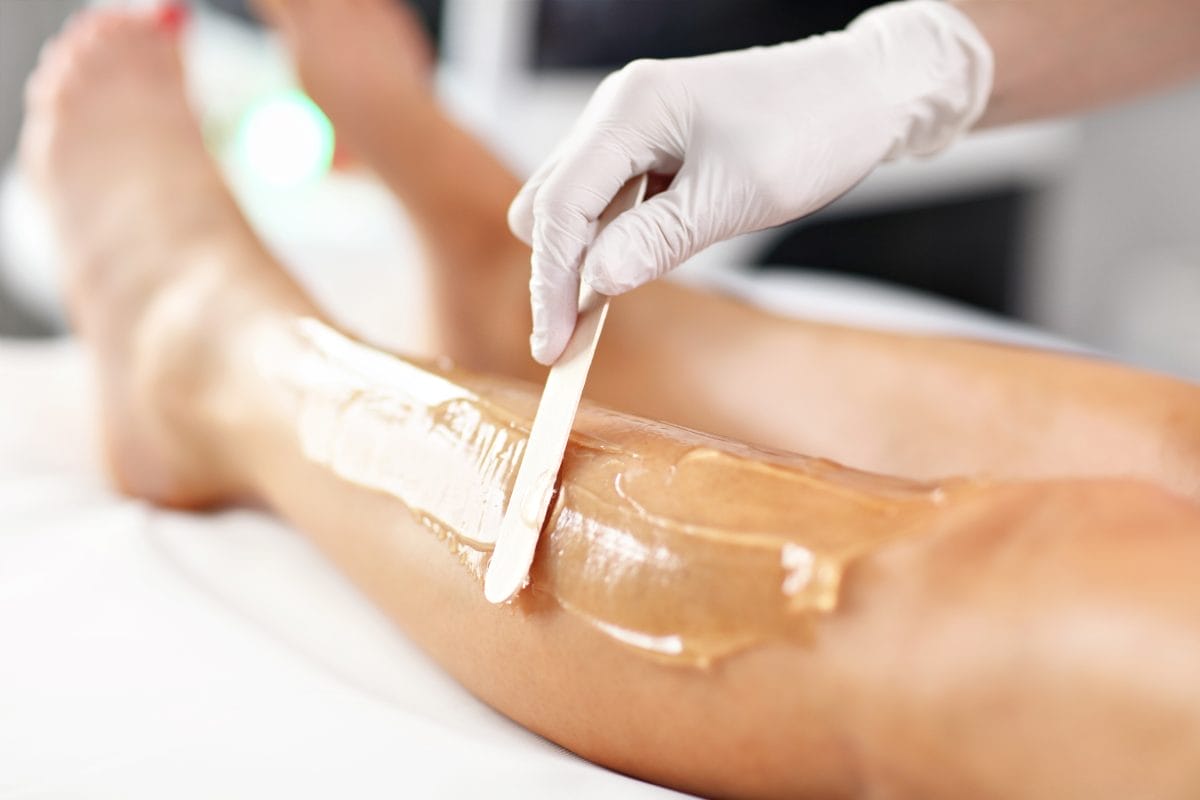 beautician giving epilation laser treatment to woman on legs