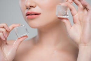 close up view of cropped woman with ice cubes isolated on grey