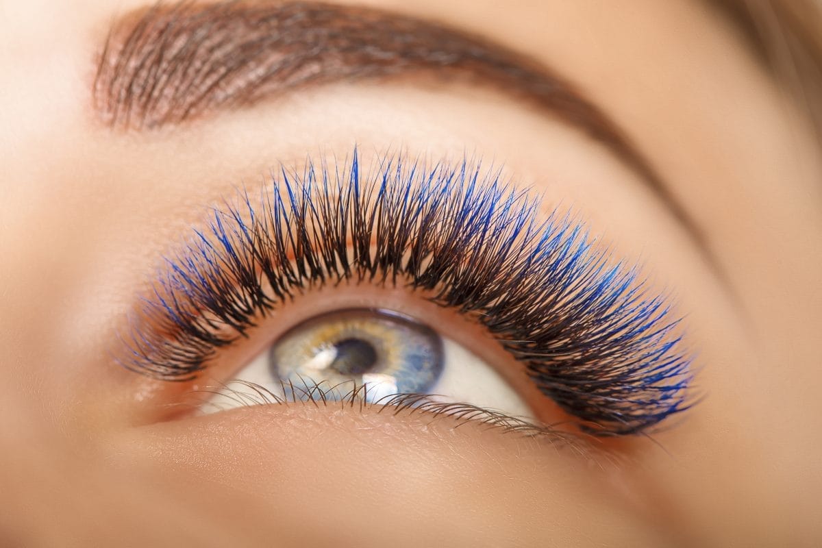 eyelash extension procedure. woman eye with long blue eyelashes. ombre effect. close up, selective focus.