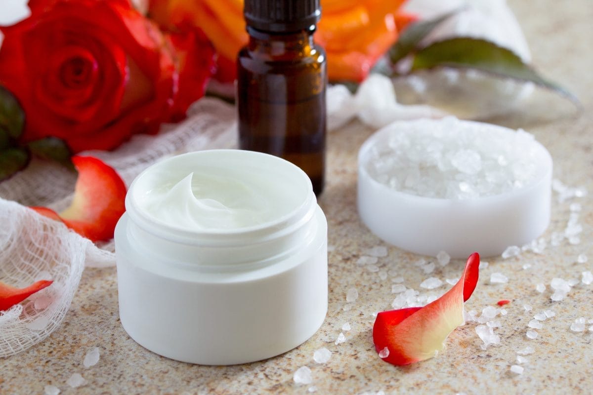 face cream with roses, bottle of aromatherapy essential oil and