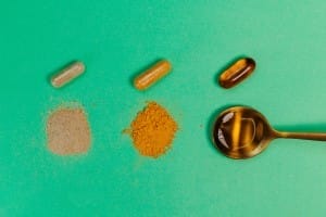 golden spoon with pills and tablets on a green background