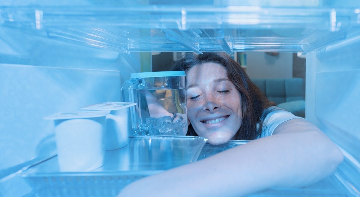 happy woman cooling herself in the fridge