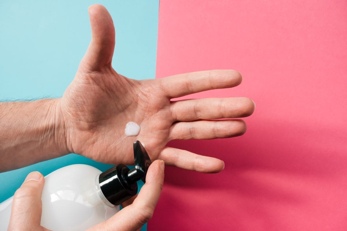 outstretched hand washing hands with soap, on a turquoise and red background.