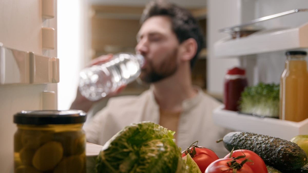 point of view pov inside refrigerator caucasian man male homeowner householder vegetarian guy open fridge with products vegetables at kitchen take out bottle with cold water drinking refreshment drink