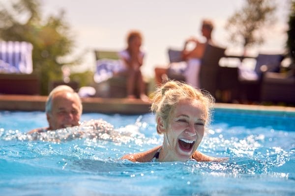 retired senior couple relaxing in swimming pool on summer vacation