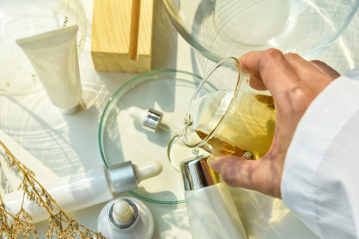 scientist mixing natural skincare beauty products, organic botany extraction and scientific laboratory glassware, blank label cosmetic container for branding mock up.