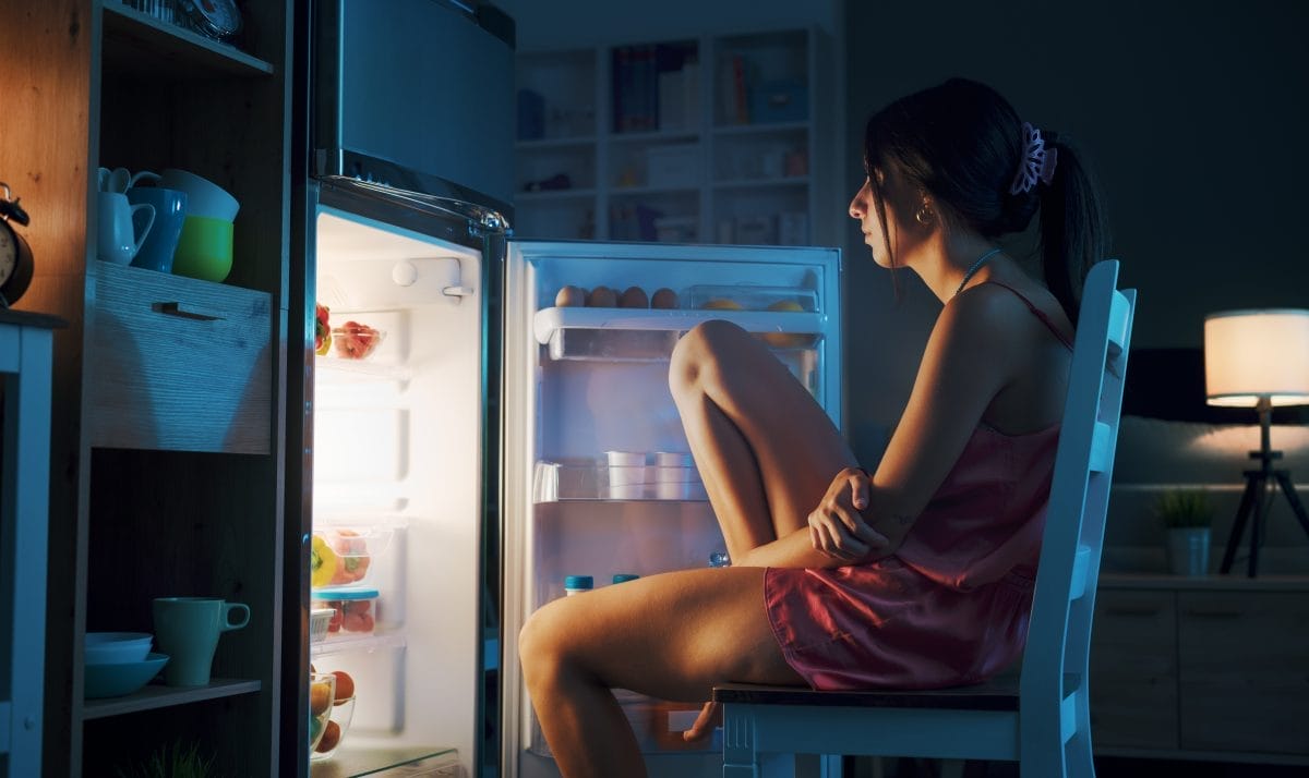 woman cooling herself in front of the open fridge