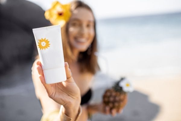 woman with sunscreen lotion on the beach