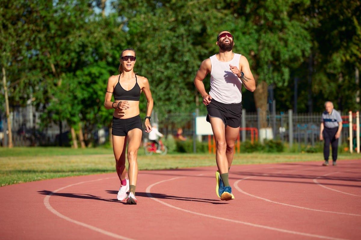 a team of track and field athletes, jointly a man and a woman, train while running.