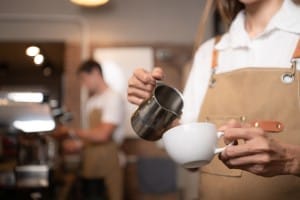 barista pouring coffee into a cup in coffee shop, closeup