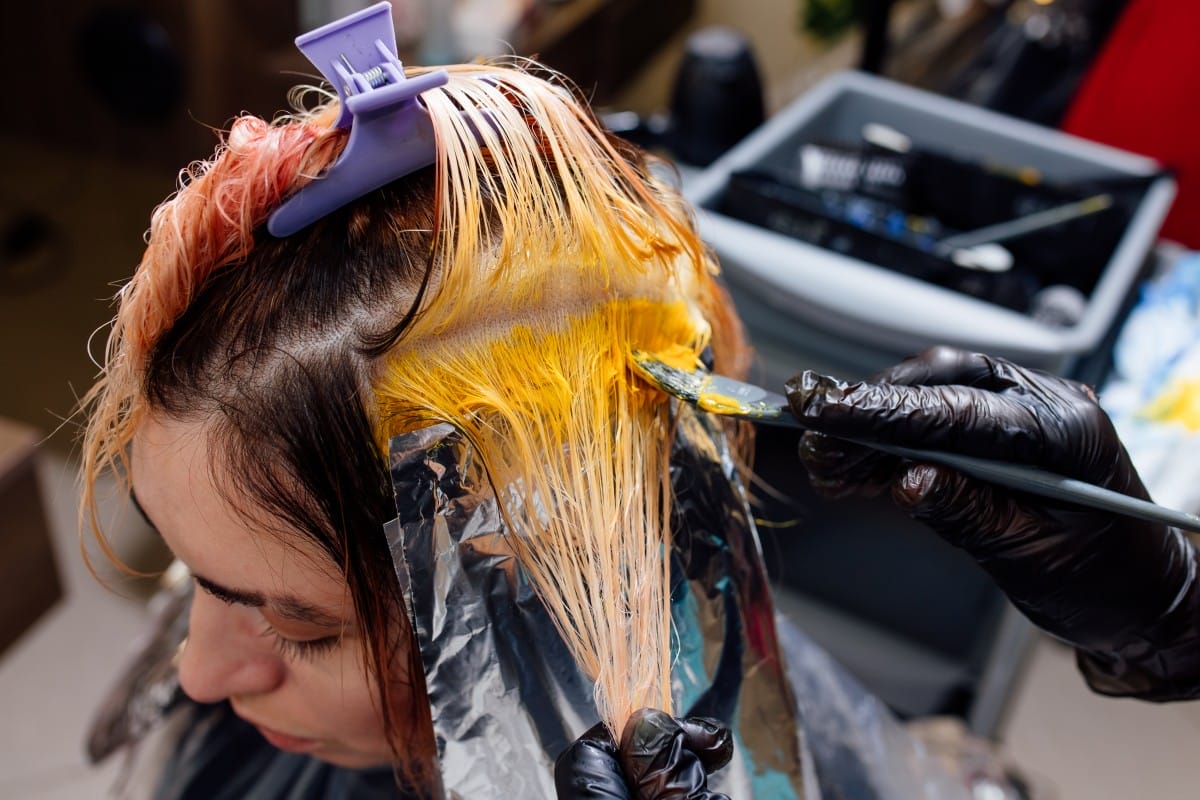 hairdresser coloring hair, applying yellow color on hair