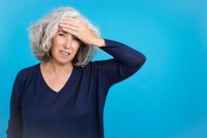 mature woman with a headache touching her forehead