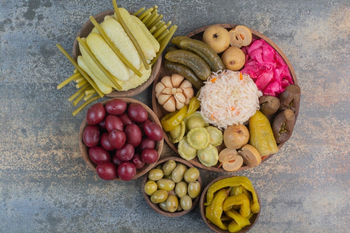 salty vegetables in wooden bowls on marble background