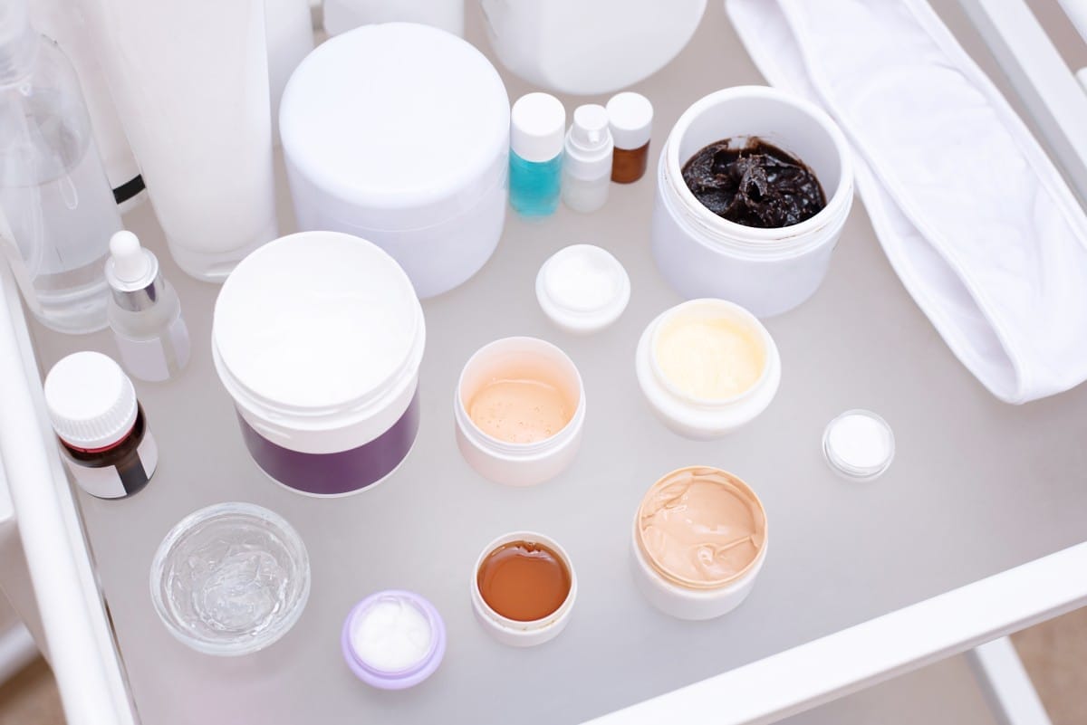 many jars with various creams on a glass table in a beauty salon, facial skin care concep.