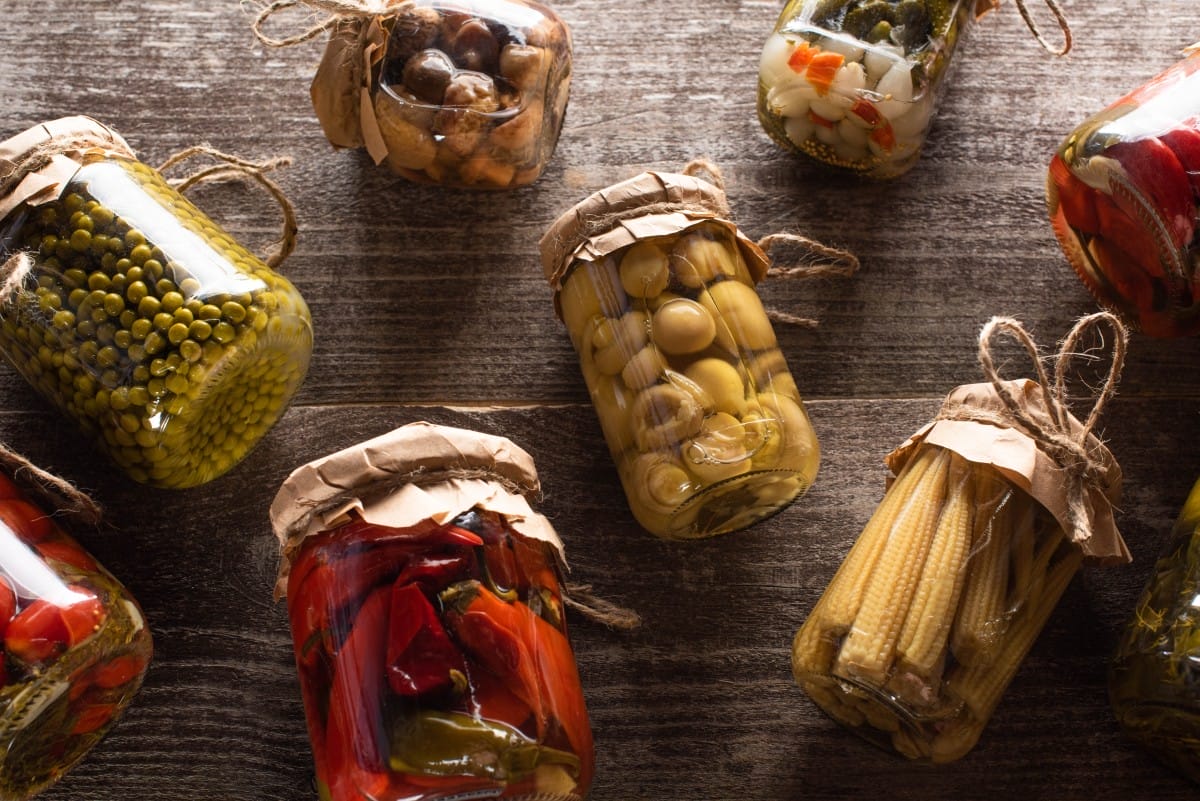 top view of homemade delicious pickles in jars on wooden table