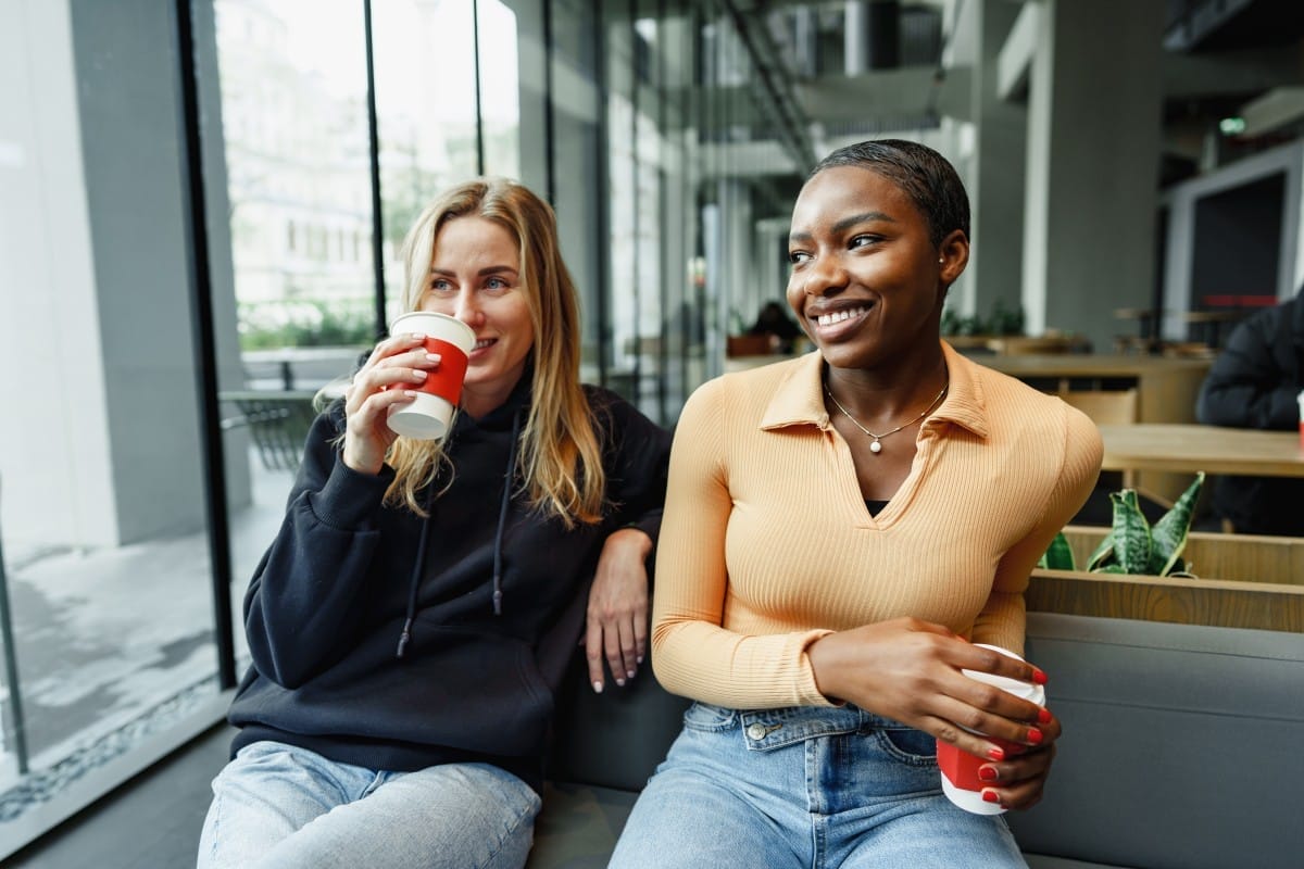 two young women friends enjoying coffee together in a coffee shop