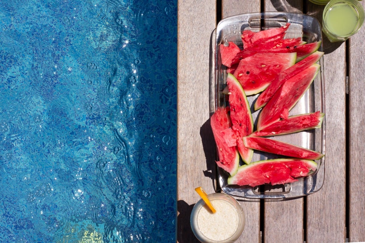 watermelon plate , and summer dkinks near pool. exotic summer di