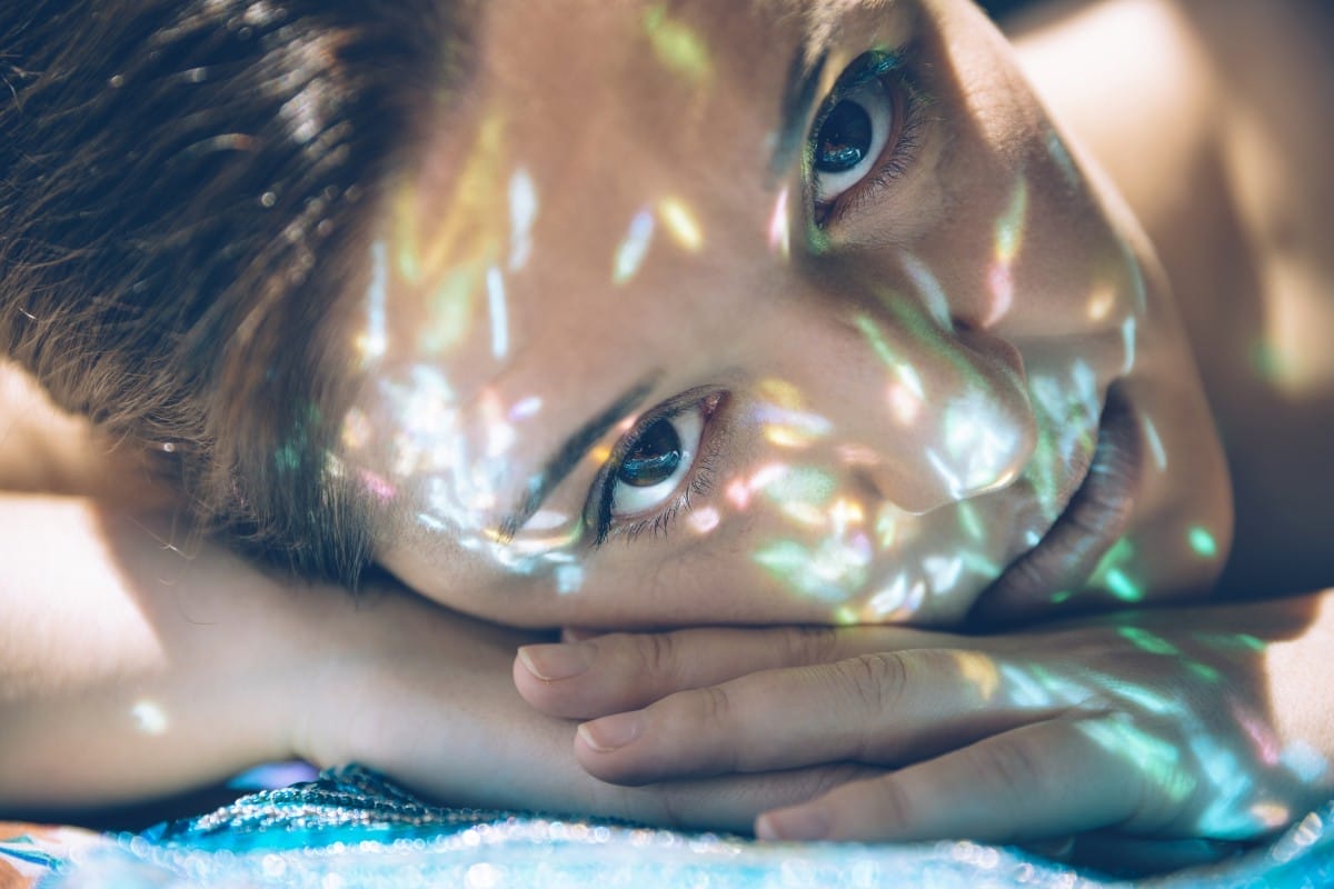 woman face over hands with sparkles in skin