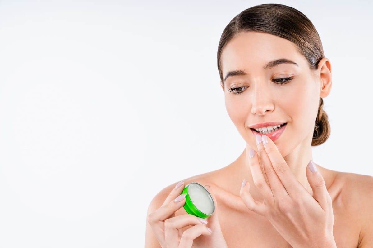 beautiful young caucasian woman applying lip balm care. make up concept