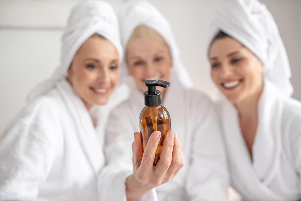 cosmetic product in hand of smiling woman and girlfriend