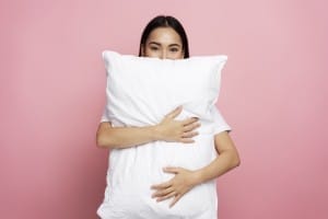 cute caucasian woman embracing pillow and looking to the camera