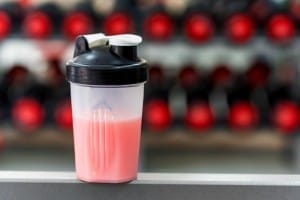 plastic shaker with strawberry protein in gym