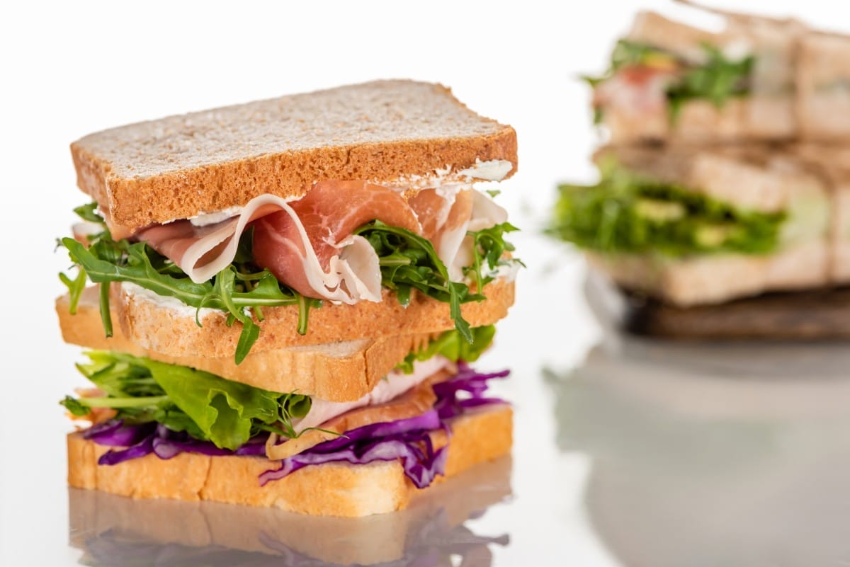 selective focus of fresh sandwiches with arugula and meat on white surface