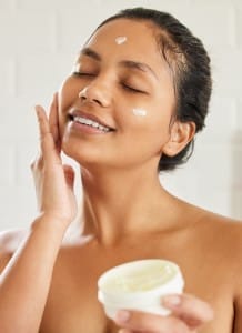 shot of young woman using with facial moisturiser at home.