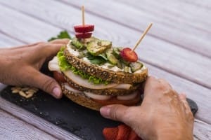 variety of ingredients in a wholemeal bread bun held in the hand