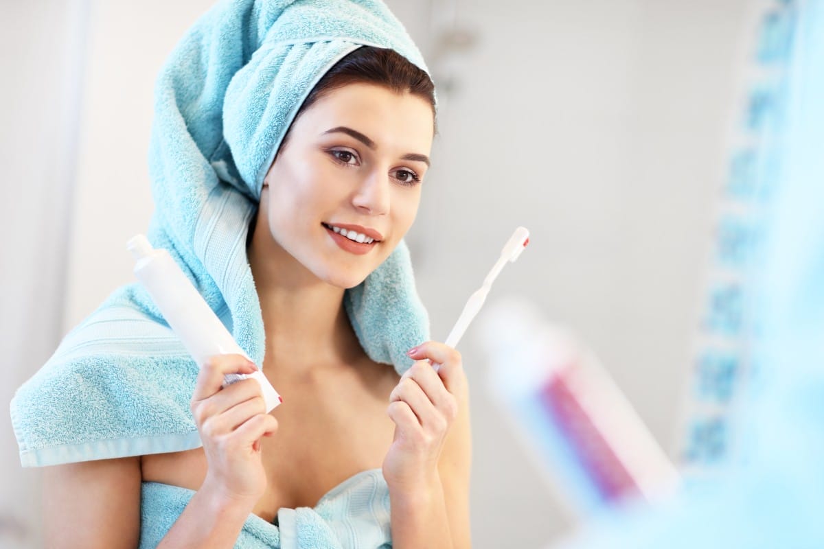 young woman washing teeth in bathroom in the morning