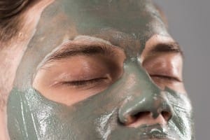 cropped view of young man with clay mask isolated on grey