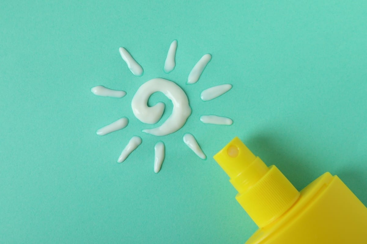 sunscreen and sun made of cream on mint background