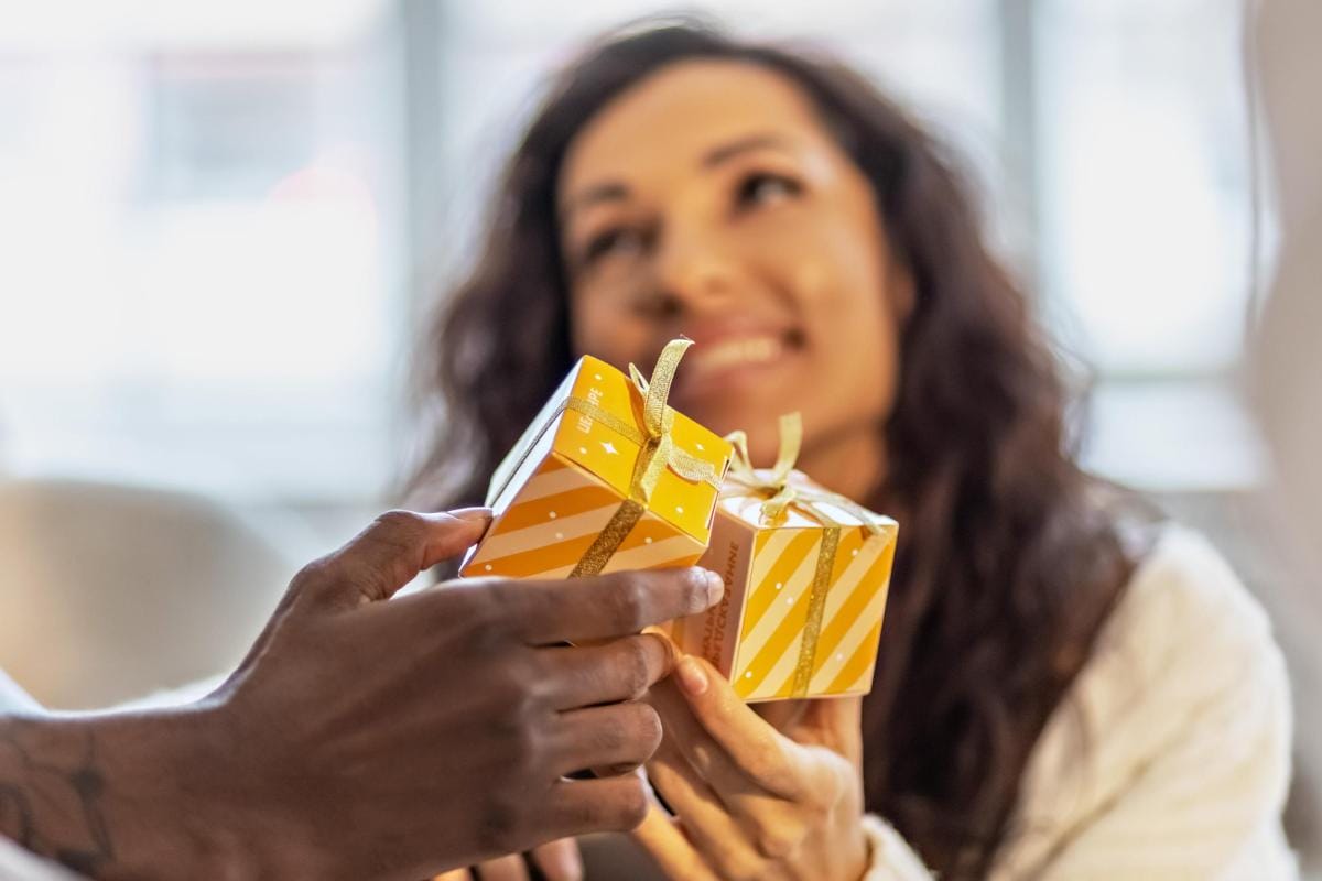 Woman receiving gift box from someone's hands