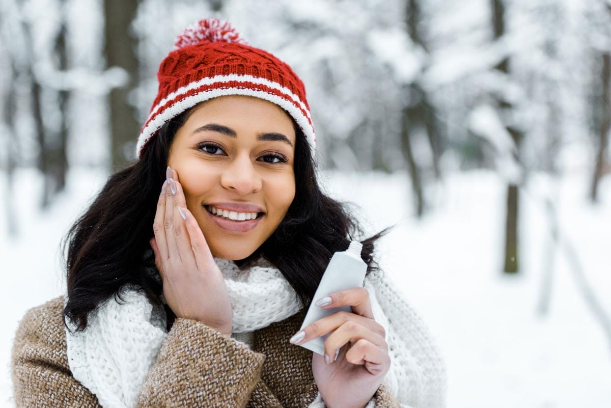 Woman applying lotion in snowy forest