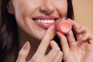 Woman smiling, applying pink lip balm