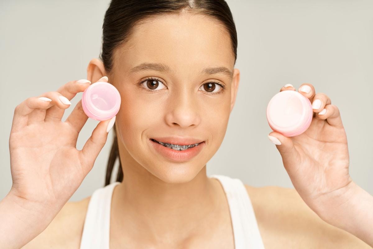 Young girl with braces holding skincare products