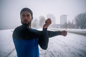 Man stretching in snowy urban setting