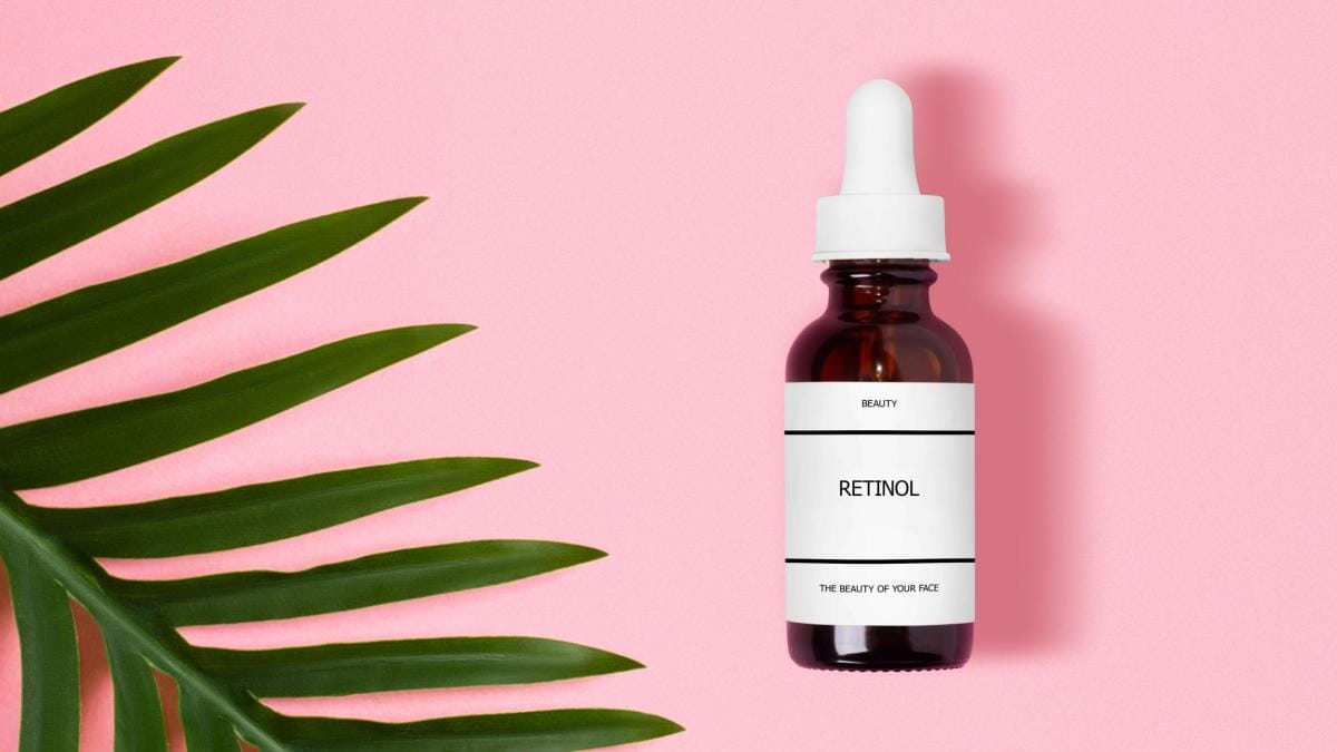 Retinol skincare serum bottle with palm leaf on pink