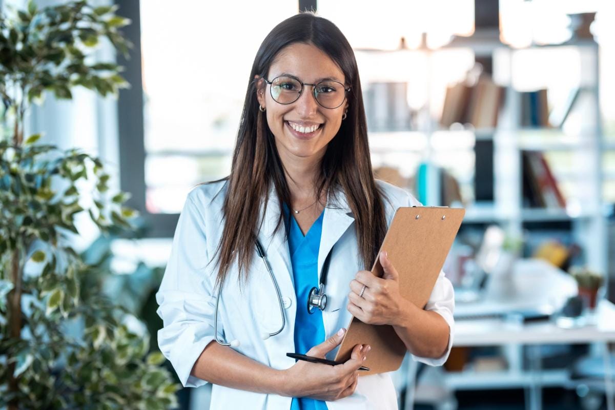 Smiling female doctor with clipboard in clinic