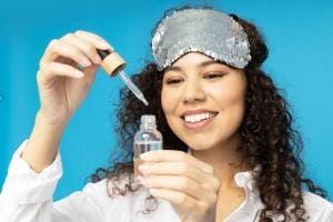 Woman with sequin sleep mask testing skincare serum