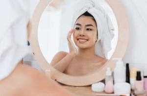 Woman applying skincare looking in round mirror