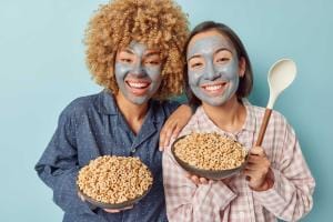 Two women with face masks holding bowls of cereal