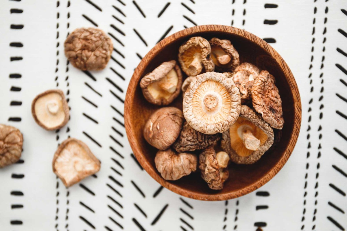 Shiitake mushrooms in wooden bowl on patterned table