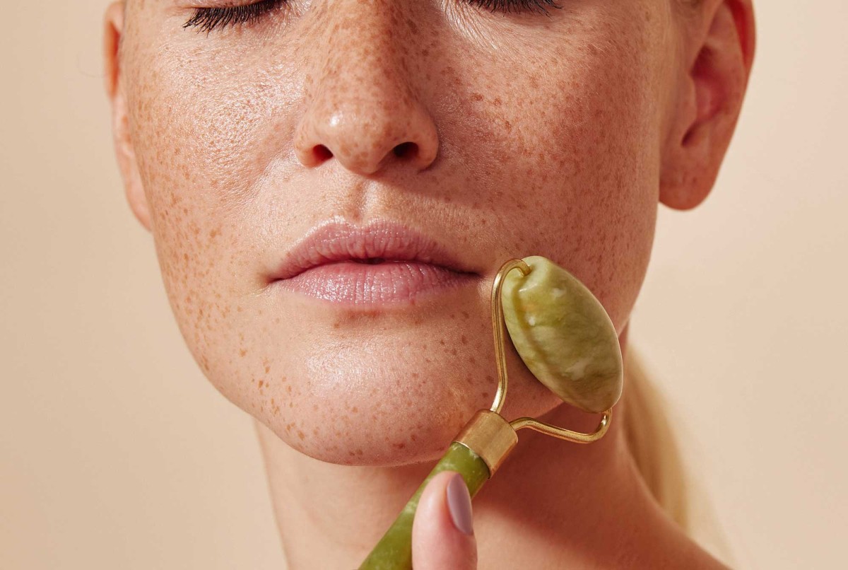 Woman using jade roller on face