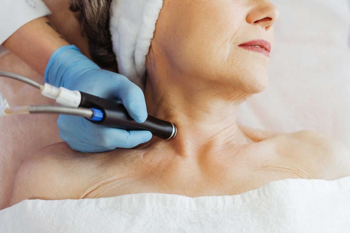 Woman receiving neck treatment in spa with medical device